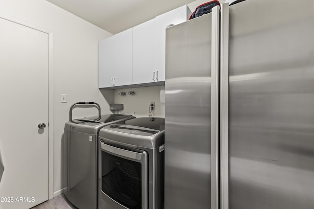 laundry area featuring separate washer and dryer and cabinet space