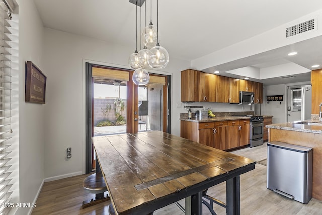 kitchen featuring stainless steel appliances, visible vents, baseboards, light wood-type flooring, and brown cabinetry