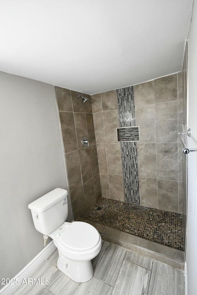 bathroom featuring a tile shower and toilet