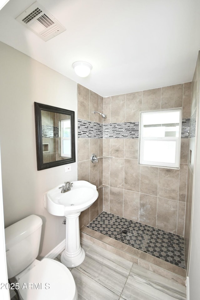 bathroom with tiled shower and toilet