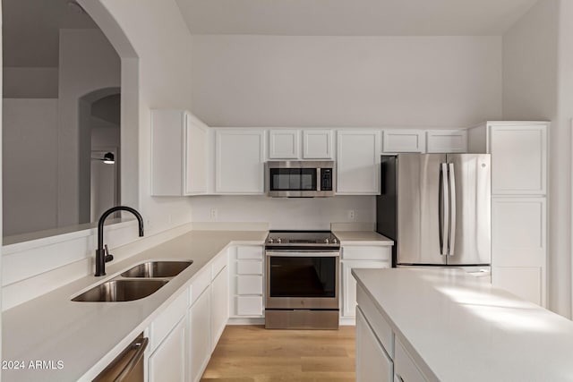 kitchen featuring sink, white cabinets, light wood-type flooring, and appliances with stainless steel finishes