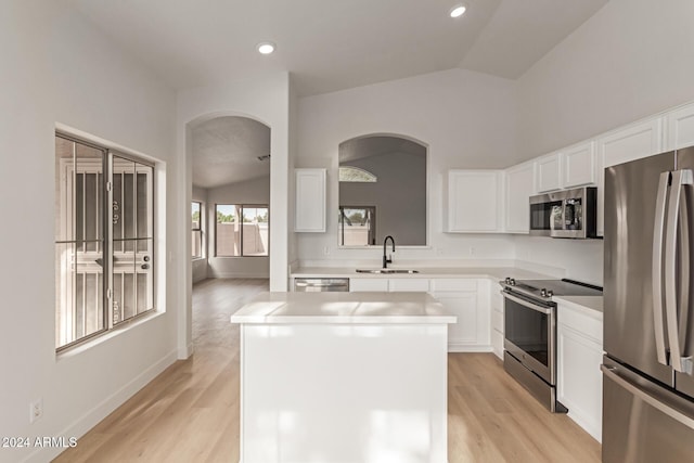 kitchen with appliances with stainless steel finishes, a kitchen island, lofted ceiling, and sink