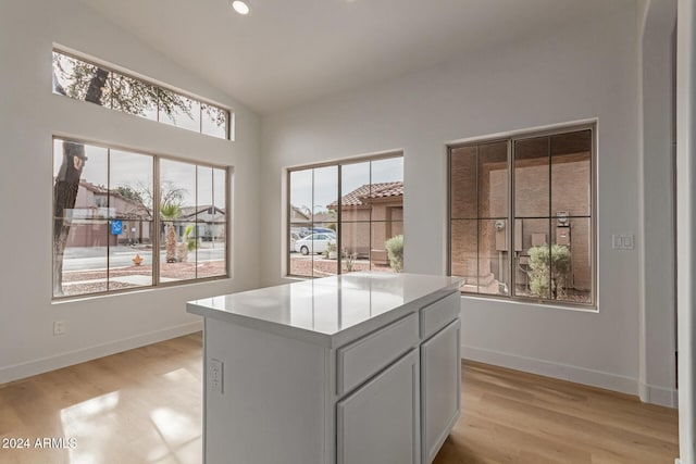 kitchen featuring light wood-type flooring, gray cabinets, a kitchen island, and lofted ceiling