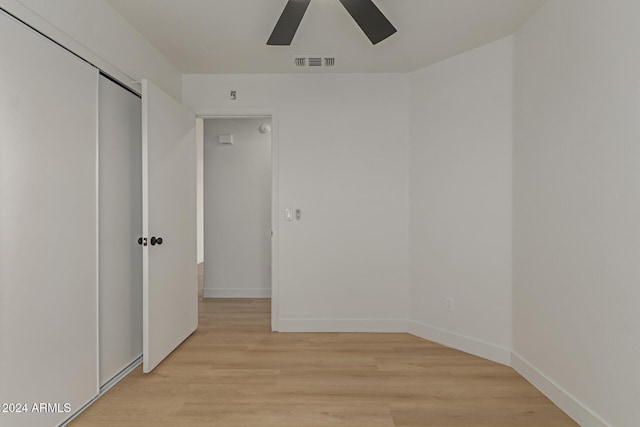 unfurnished bedroom with ceiling fan, a closet, and light hardwood / wood-style flooring