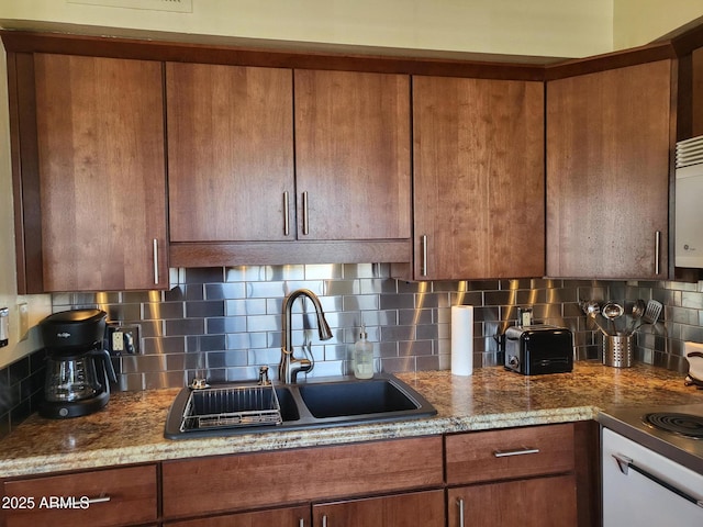 8220 E Garfield St Unit M214, Scottsdale, AZ 85257 - kitchen with brown cabinetry, backsplash, stone counters, and a sink