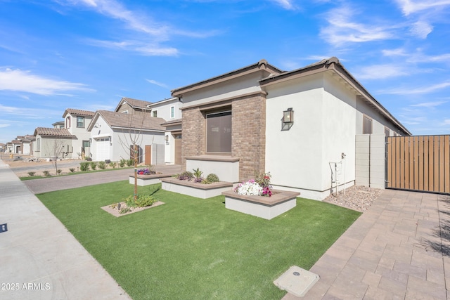 view of front facade featuring a residential view, a gate, fence, a front yard, and stucco siding