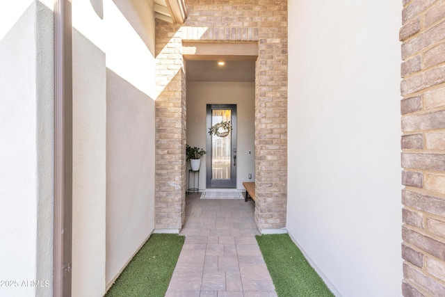 view of exterior entry with brick siding and stucco siding