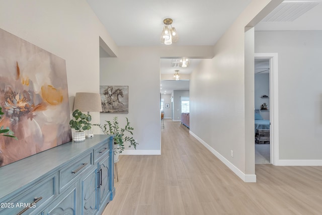 corridor featuring baseboards, visible vents, and light wood-style floors