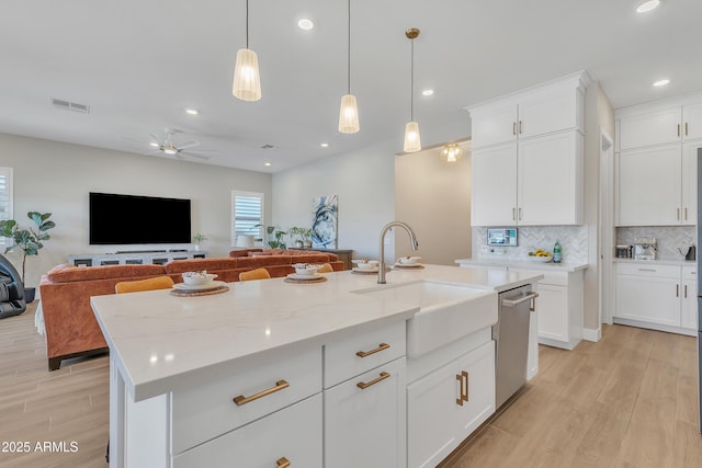 kitchen with tasteful backsplash, visible vents, light wood-style floors, a sink, and dishwasher