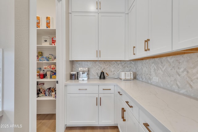 interior space featuring light stone counters, white cabinets, and decorative backsplash