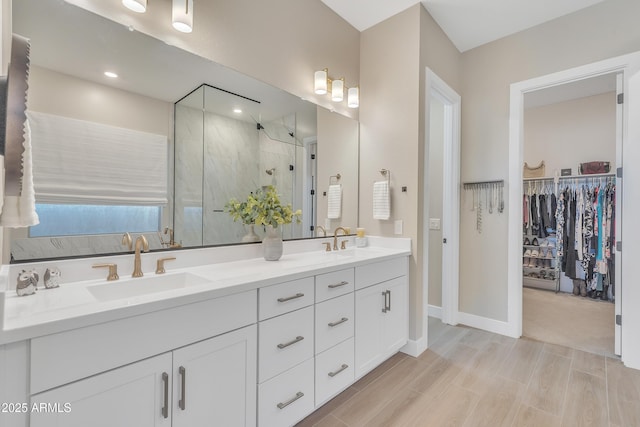 full bath featuring a stall shower, a walk in closet, a sink, and double vanity