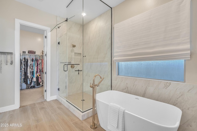 bathroom featuring a walk in closet, tile walls, a freestanding bath, wood tiled floor, and a shower stall