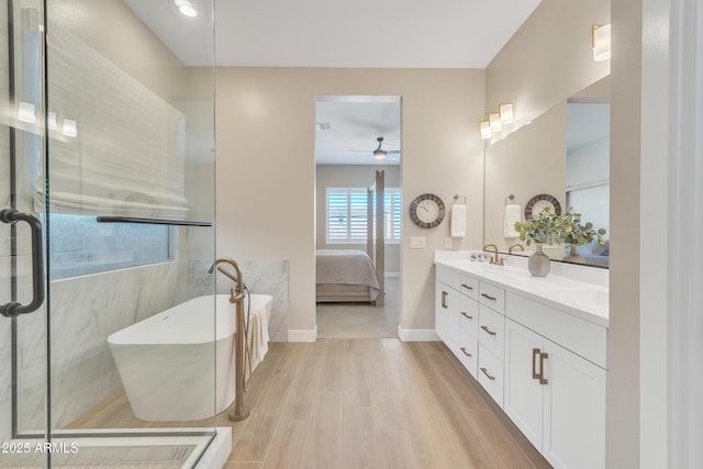 full bathroom with double vanity, a soaking tub, connected bathroom, wood finished floors, and baseboards