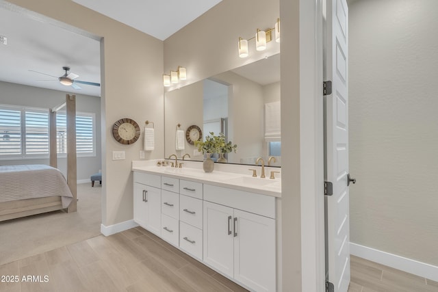 bathroom with double vanity, wood tiled floor, baseboards, and a sink