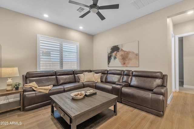 living area with visible vents, light wood-type flooring, a ceiling fan, and baseboards