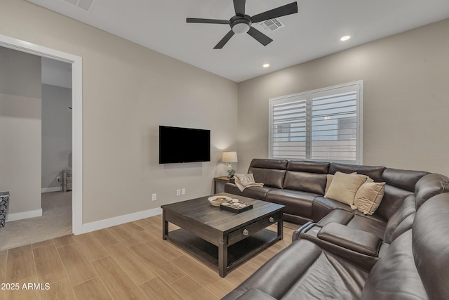 living room with light wood-type flooring, visible vents, ceiling fan, and baseboards