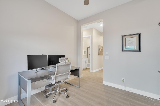 office space with light wood-style floors, ceiling fan, baseboards, and vaulted ceiling