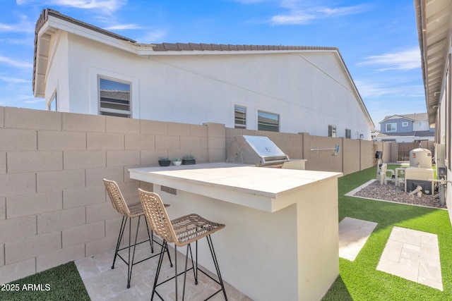 view of patio / terrace with a fenced backyard, area for grilling, a grill, and outdoor wet bar