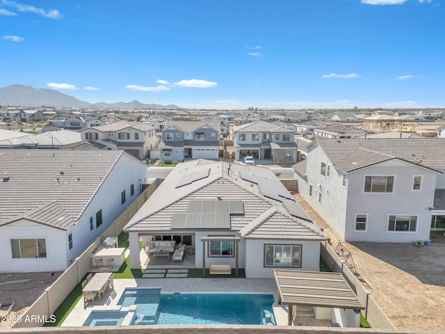 back of property featuring solar panels, a residential view, a patio area, a pool with connected hot tub, and a mountain view