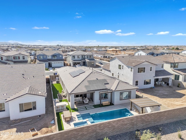 back of property with a pool with connected hot tub, a residential view, a fenced backyard, and a tile roof