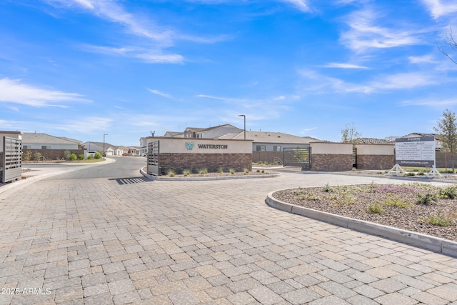 view of street featuring a residential view, curbs, a gated entry, and street lights