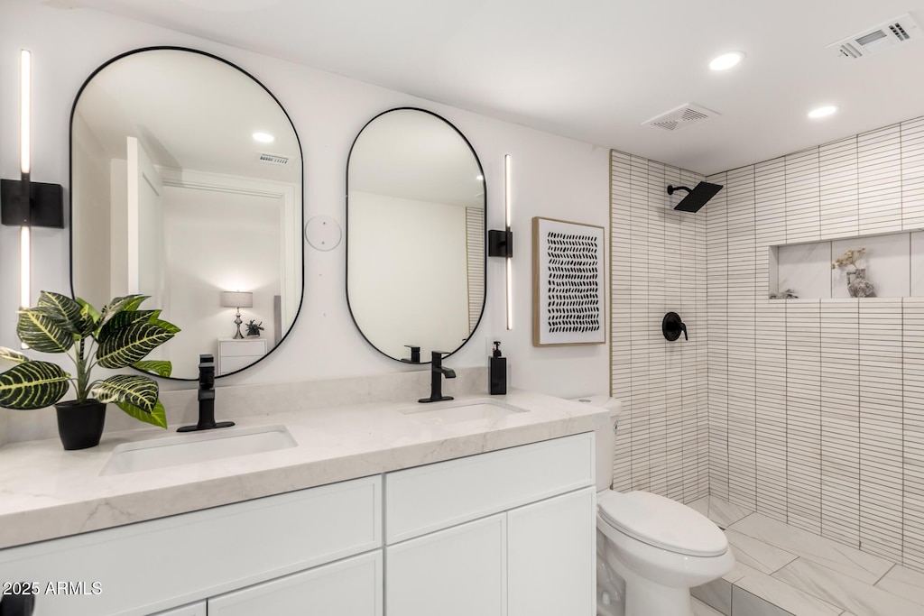 bathroom with vanity, toilet, and a tile shower