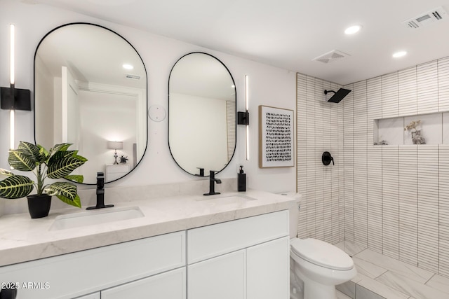 bathroom with vanity, toilet, and a tile shower