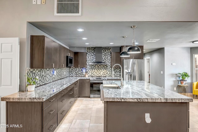 2405 E Lynwood Cir, Mesa, AZ 85213 - kitchen featuring appliances with stainless steel finishes, wall chimney range hood, decorative backsplash, dark brown cabinetry, and an island with sink