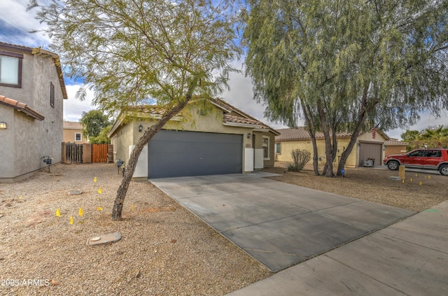 view of front of home with fence, driveway, stucco siding, a garage, and a tiled roof