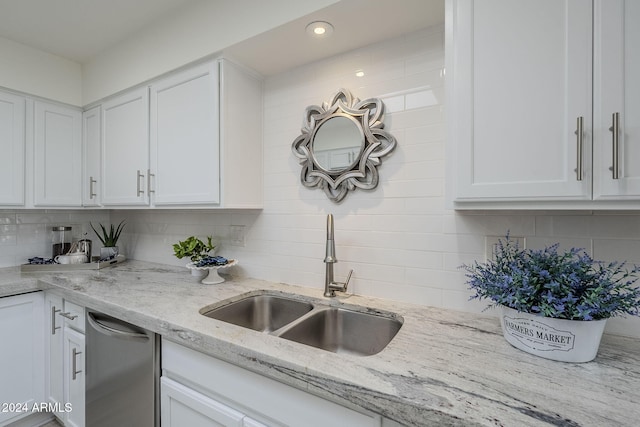 kitchen featuring decorative backsplash, light stone counters, sink, dishwasher, and white cabinetry