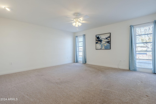 carpeted empty room featuring ceiling fan and a wealth of natural light