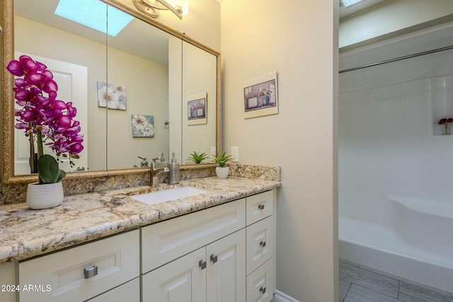 bathroom with a shower, vanity, and a skylight