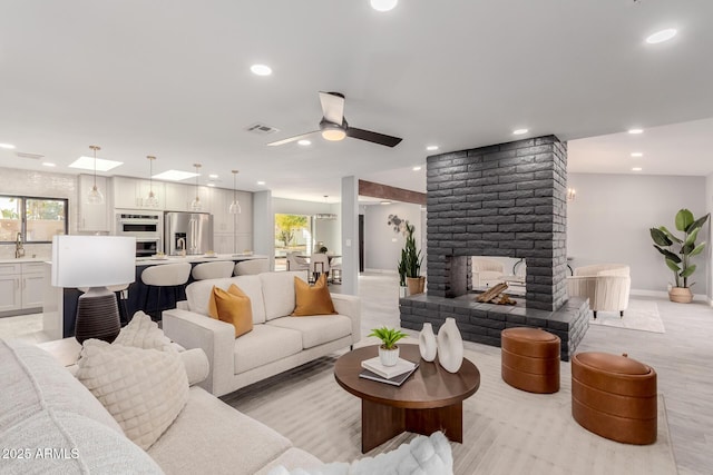 living room featuring ceiling fan, sink, and a fireplace