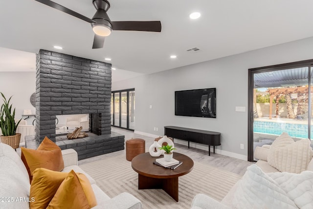 living room featuring a fireplace, light hardwood / wood-style floors, and ceiling fan