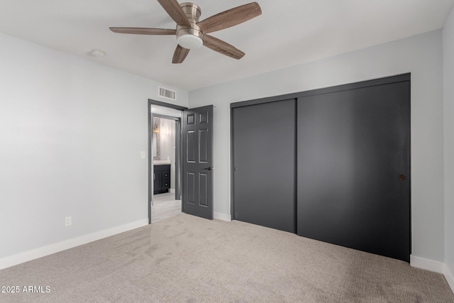 unfurnished bedroom featuring ceiling fan, a closet, and light carpet