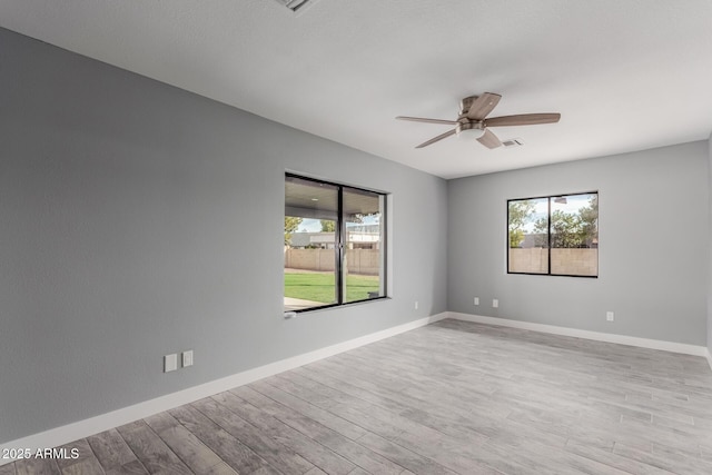 empty room with ceiling fan and light hardwood / wood-style flooring