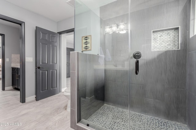 bathroom featuring a tile shower, hardwood / wood-style floors, vanity, and toilet