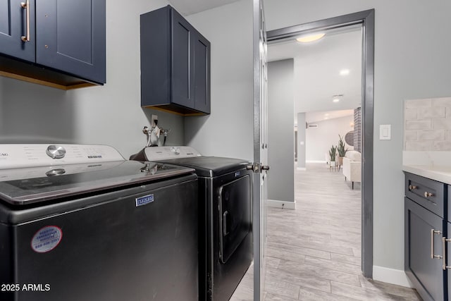 laundry room featuring cabinets, independent washer and dryer, and light hardwood / wood-style floors