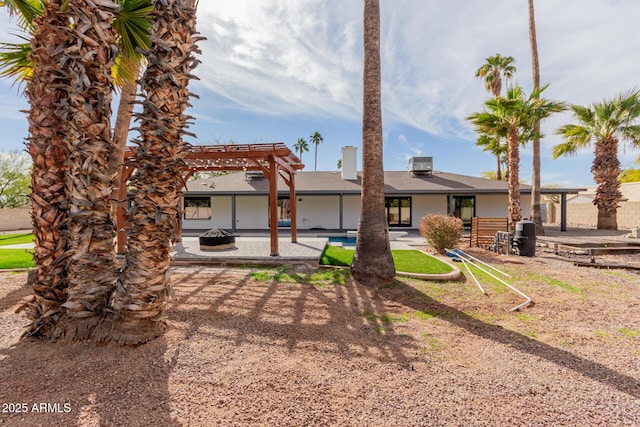 rear view of property featuring a fire pit, a pergola, and a patio