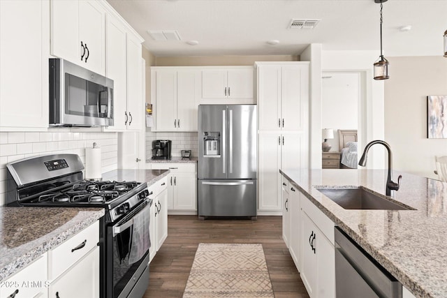 kitchen with white cabinetry, sink, light stone countertops, and appliances with stainless steel finishes