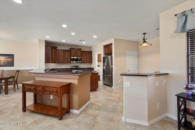 kitchen featuring a kitchen bar, kitchen peninsula, stainless steel appliances, hanging light fixtures, and dark stone counters