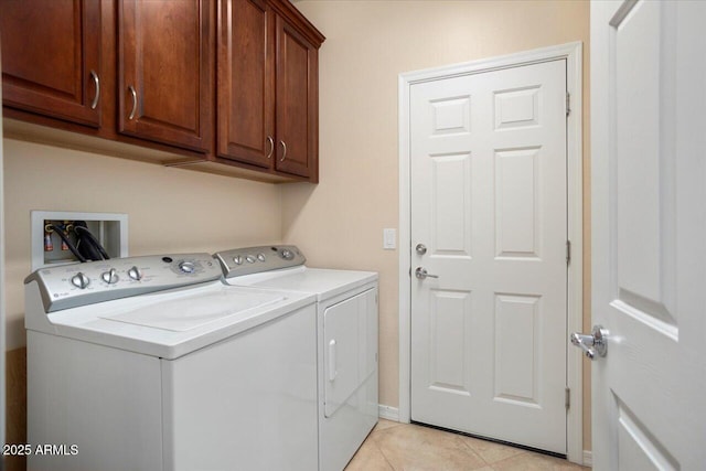 laundry room with washer and clothes dryer, light tile patterned floors, and cabinets