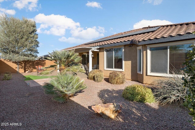 rear view of house featuring solar panels and a patio