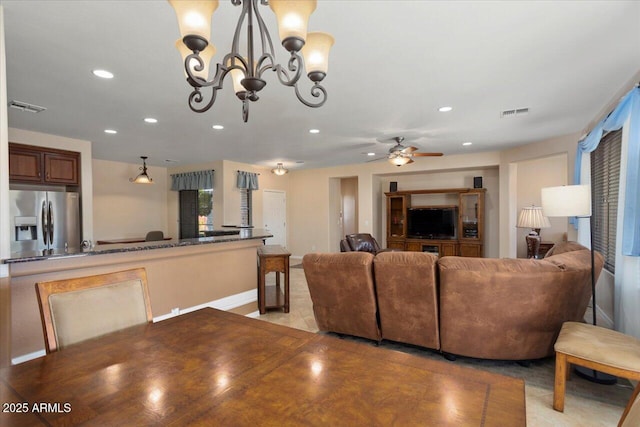 living room with ceiling fan with notable chandelier