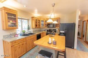 3458 N Meadow Dr, Pine, AZ 85544 - kitchen featuring black refrigerator with ice dispenser, stove, light countertops, hanging light fixtures, and glass insert cabinets