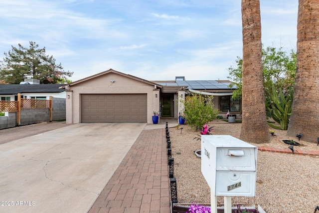 single story home featuring solar panels, stucco siding, concrete driveway, an attached garage, and fence