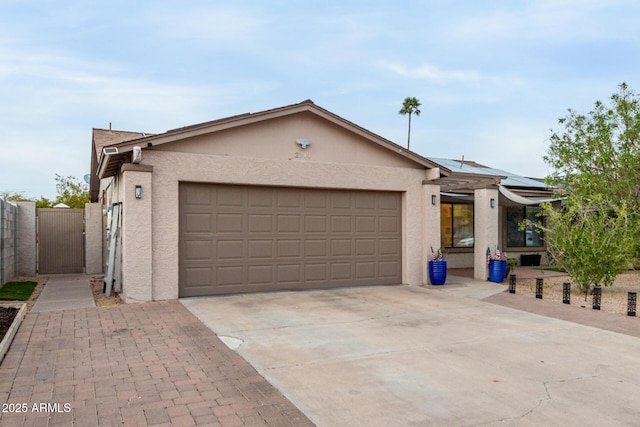 ranch-style home featuring a garage, concrete driveway, roof mounted solar panels, and stucco siding