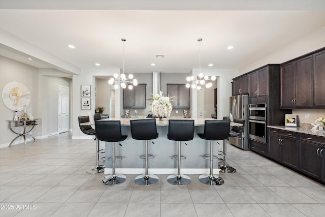 23060 E Sonoqui Blvd, Queen Creek, AZ 85142 - kitchen featuring a chandelier, appliances with stainless steel finishes, wall chimney range hood, dark brown cabinets, and light tile patterned floors