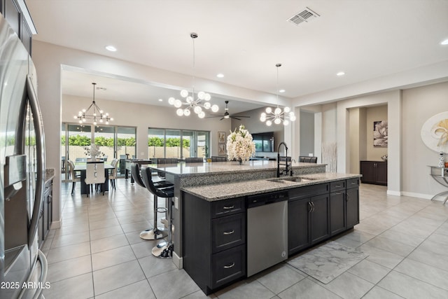 23060 E Sonoqui Blvd, Queen Creek, AZ 85142 - kitchen featuring appliances with stainless steel finishes, a chandelier, dark cabinetry, a kitchen island with sink, and light tile patterned floors