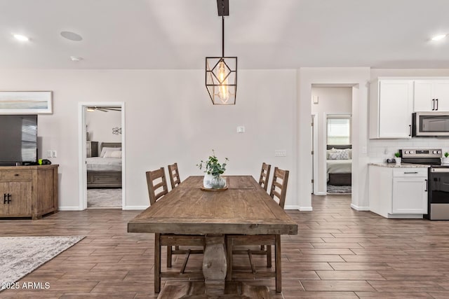 dining room with dark wood-style floors, a ceiling fan, and baseboards